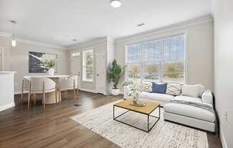 A living room with a white couch, a coffee table, and a dining table with chairs.