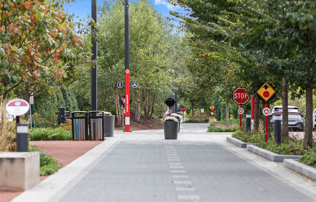 a city sidewalk with trees and a stop sign