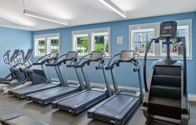 a row of treadmills and elliptical trainers in a fitness room