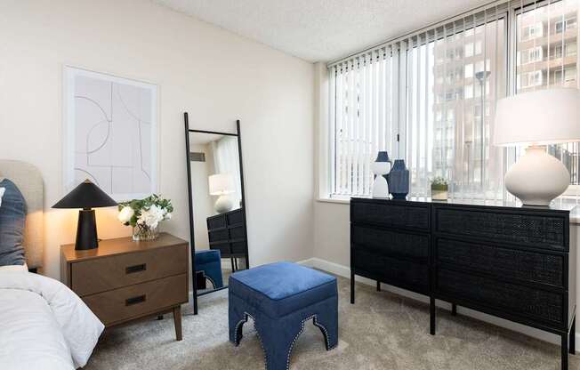 a bedroom with a large window and a bed with a blue ottoman