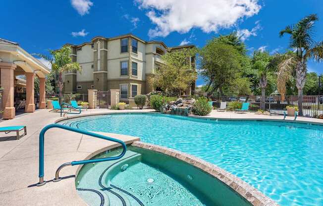 A swimming pool in front of a building with a blue sky in the background.