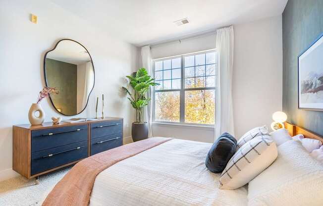 A bedroom with a bed, dresser, and mirror.
