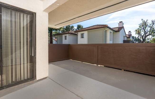 A patio with a white wall and a brown fence.