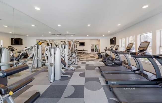 a gym with cardio equipment and weights on a checkered floor at Paisley and Pointe Apartments, Las Vegas, Nevada