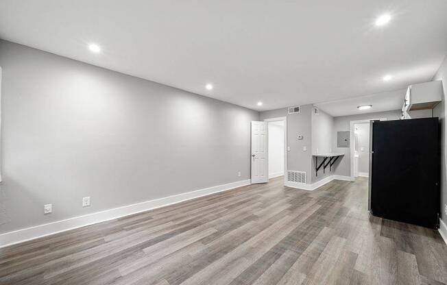 A spacious room with wooden flooring and white walls.