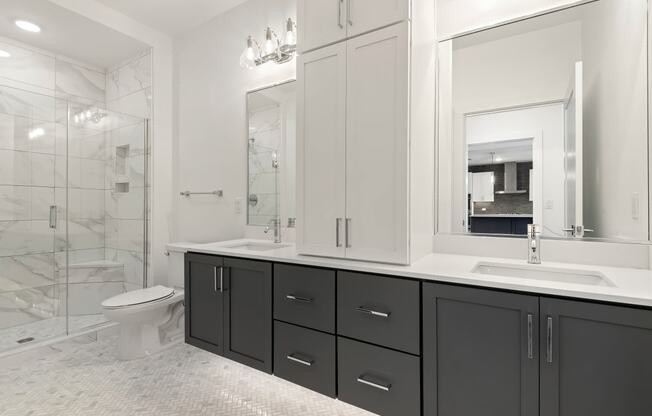 a white and black bathroom with black cabinets and a white toilet