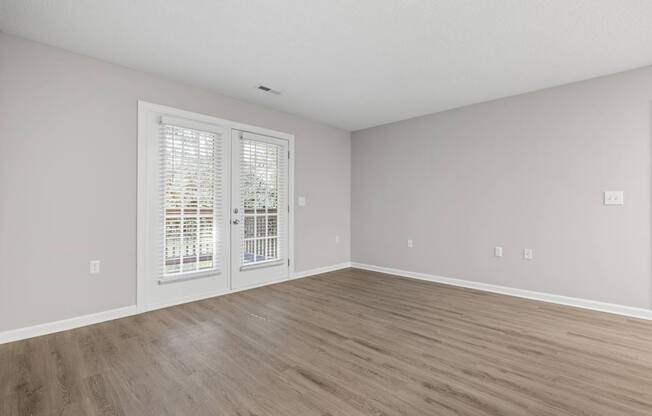 A room with a sliding glass door and wooden flooring.