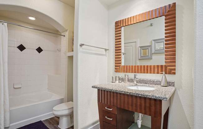 A bathroom with a white tub and a wooden vanity.