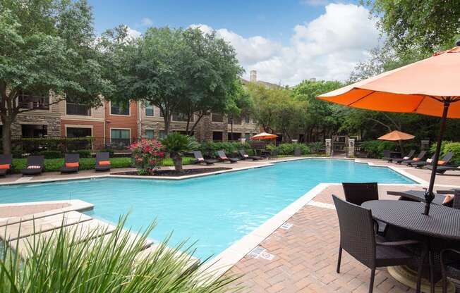 a pool with lounge chairs and umbrellas at the oxford at the boulevard apartments