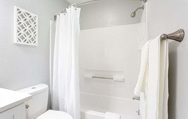 A white bathroom with a toilet, sink, and shower.
