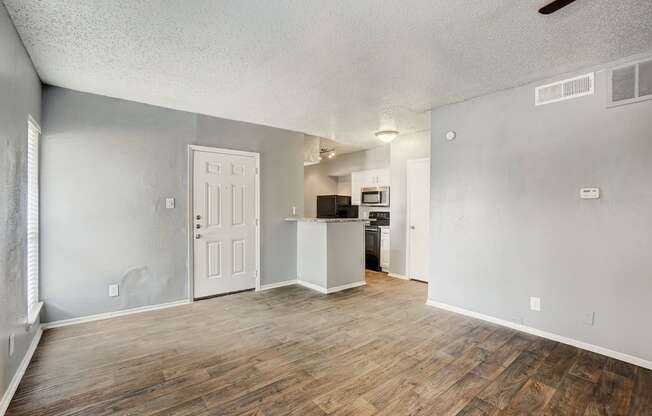 the living room and kitchen of an apartment with a hard wood floor