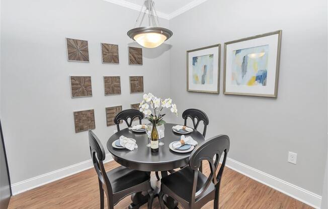 Corner view of a dining room with a hanging light, crown molding, hard floors, and a wall outlet