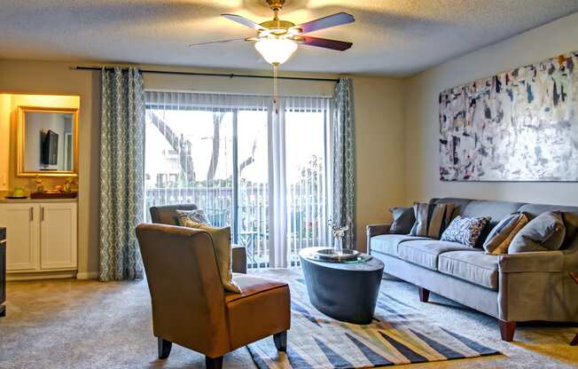 a living room with a couch and chair and a ceiling fan