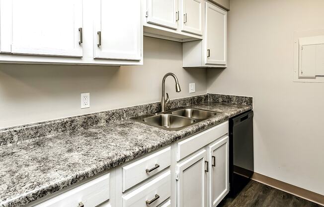 a kitchen with white cabinets and granite counter tops and a sink