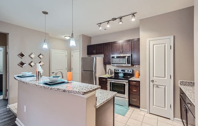 A kitchen with a granite countertop and stainless steel appliances.