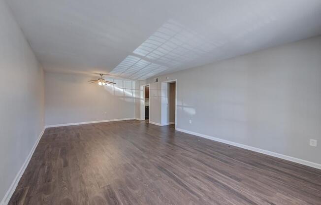 A room with a ceiling fan and light, and a door leading to another room.