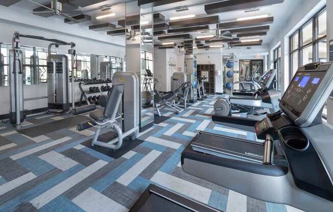 a gym with treadmills and other exercise equipment in a building with windows at The Hendrix, Atlanta