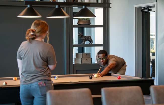 A man and a woman playing pool in a room.
