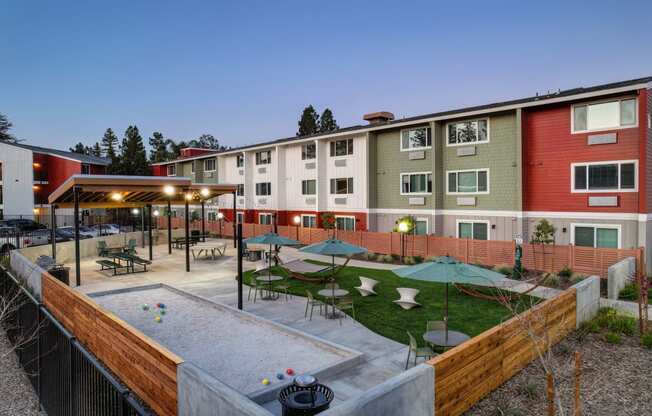 a courtyard with tables and umbrellas in front of an apartment building