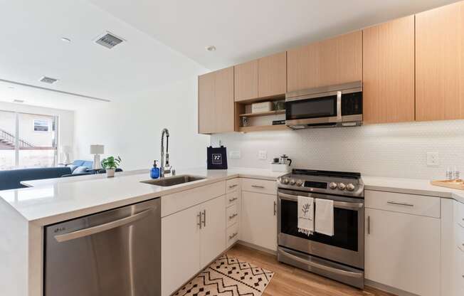 an apartment kitchen with stainless steel appliances and wooden cabinets