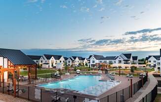 A large outdoor swimming pool surrounded by a fence and a wooden pergola.