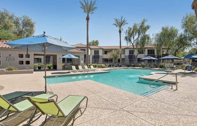 a swimming pool with chairs and umbrellas and a building in the background