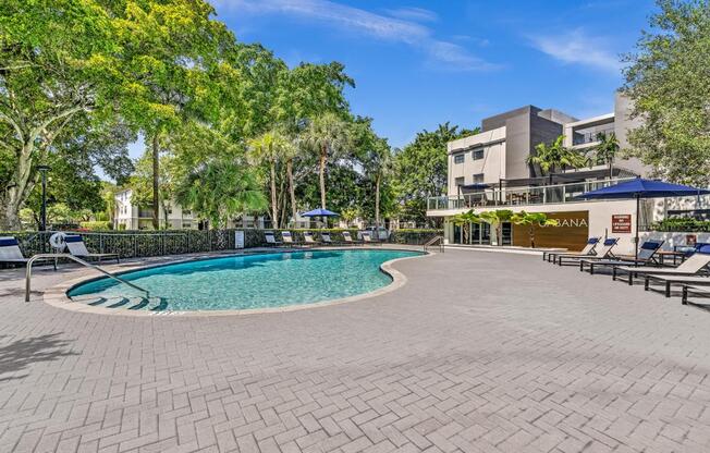 A pool surrounded by a brick patio and trees.