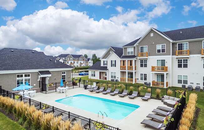 a swimming pool with lounge chairs in front of apartment buildings