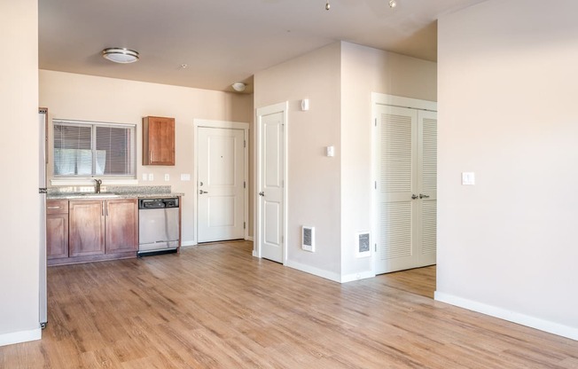 an empty kitchen and living room with wood flooring and white walls