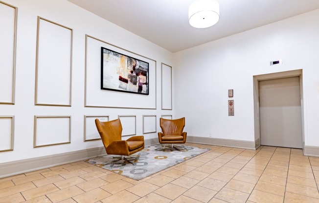 a lobby with two chairs and a painting on the wall at 26 West, Managed by Buckingham Urban Living, Indianapolis