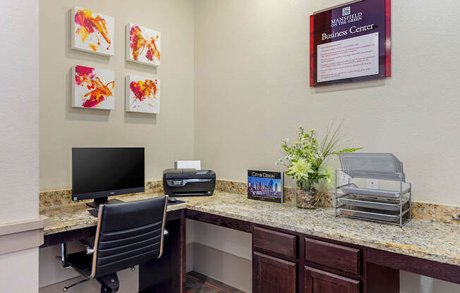 a desk with a computer and a printer in a lobby