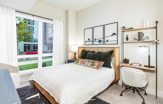 This bright and thoughtfully designed bedroom features plush carpeting, natural light, and a built-in workspace to help you recharge and refocus.