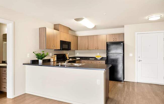 A kitchen with a black fridge and wooden cabinets.