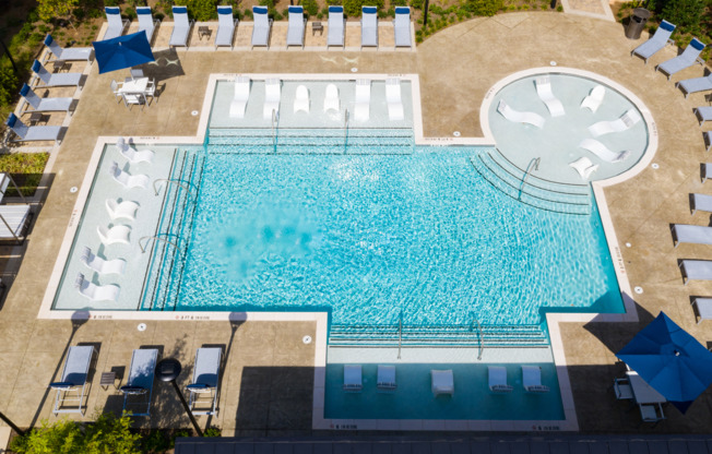 Aerial photo of the pool area at our apartments in Atlanta, GA featuring reclining chairs, shade structure, and umbrellas.