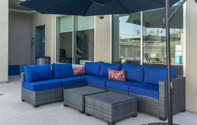 a patio with a blue sectional sofa and gray wicker chairs at Loma Villas Apartments, California