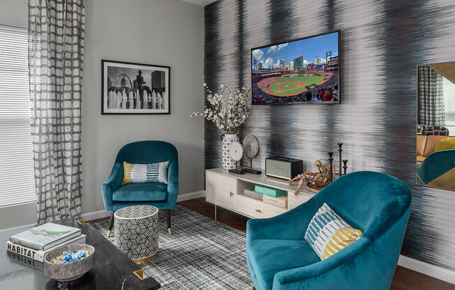 a living room with blue chairs and a tv on the wall
