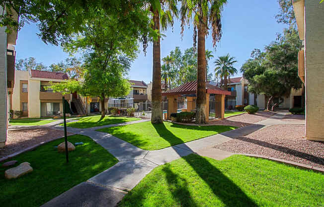 a courtyard with trees and buildings with grass and sidewalks