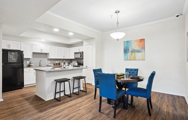 a living room with a table and chairs and a kitchen with a sink at La Ventura Apartments, Texas, 75093