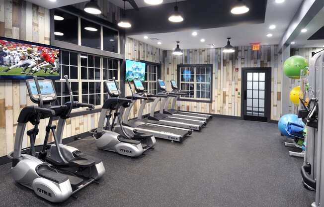 a gym with treadmills and weights and a tv at Willowest in Lindbergh, Georgia