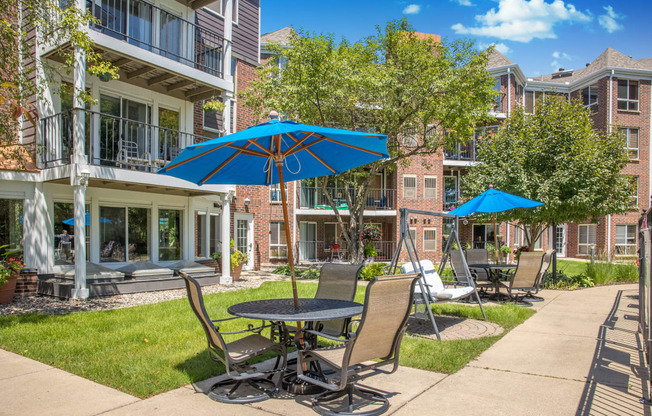 a patio with tables and chairs and umbrellas in front of an apartment building