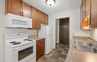 A kitchen with white appliances and wooden cabinets.