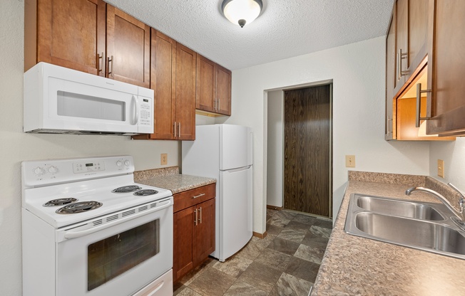 A kitchen with white appliances and wooden cabinets.