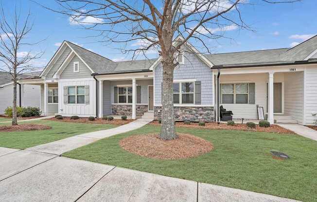 A house with a grey roof and white walls with a tree in front.