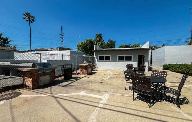 a patio with a table and chairs and a grill