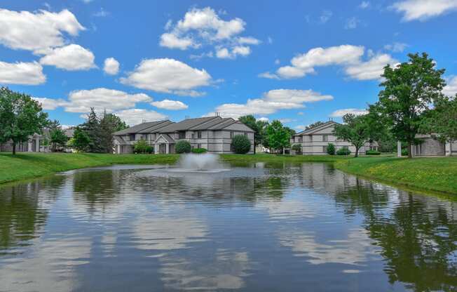 a pond in front of a house with a fountain