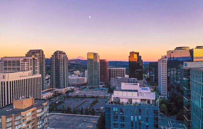 A cityscape at dusk with buildings and a clear sky.