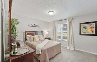 A bedroom with a bed, nightstand, and a painting on the wall.