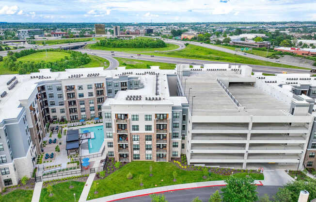 A large apartment complex with a pool and a parking garage.