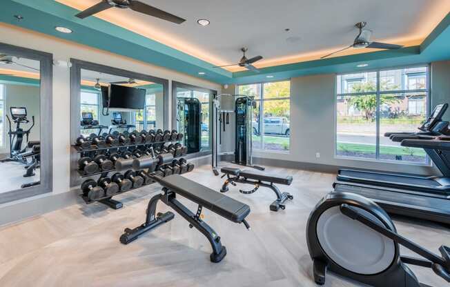 a gym with treadmills and other fitness equipment in a building with windows