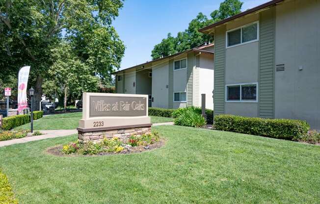 View of exterior of buildings with monument of Villas at Fair Oaks Logo